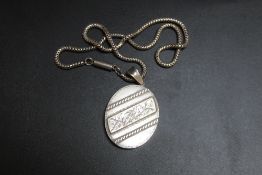 AN ANTIQUE LOCKET, in unmarked white metal on snake link style chain, H 6 cm inc bail