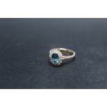 A HALLMARKED 9 CARAT GOLD RING, set with a blue aqua marine style stone surrounded by diamonds,