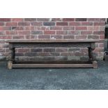A NINETEENTH CENTURY OAK CARVED BENCH, raised on four carved baluster supports united by stretchers,