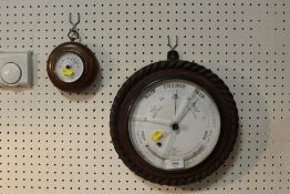 A CARVED OAK CIRCULAR WALL BAROMETER TOGETHER WITH A SMALLER EXAMPLE (2)