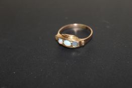 AN UNMARKED YELLOW METAL THREE STONE OPAL STYLE RING
