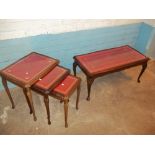 A LEATHER INLAID GLASS TOPPED NEST OF THREE TABLES AND A MATCHING COFFEE TABLE