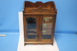 AN ANTIQUE GLAZED TWO DOOR SMOKER'S CABINET FITTED WITH THREE DRAWERS