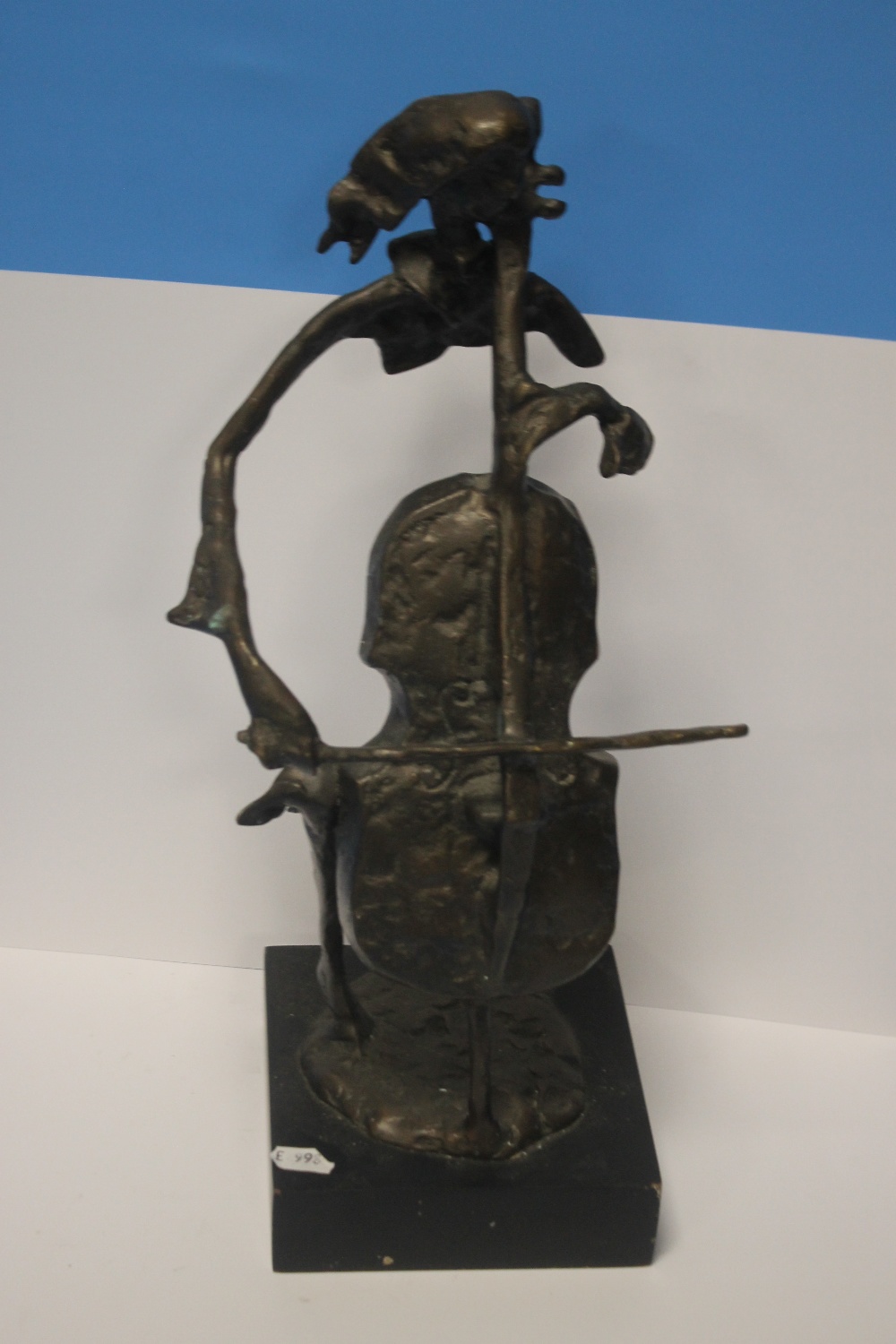 A METAL MODERN ART FIGURE OF A LADY PLAYING A CELLO ON WOODEN PLINTH