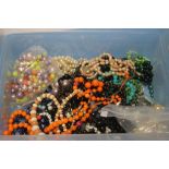A TUB OF OF ASSORTED COSTUME NECKLACES AND A BAG OF BEADS ETC.