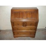 AN OAK BUREAU WITH LEATHER INLAY AND LINENFOLD DESIGN