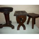 AN ADJUSTABLE ANTIQUE PIANO STOOL, AN OAK CARVED SIDE TABLE AND A THREE LEGGED MILKING STOOL (3)