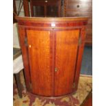 A 19TH CENTURY OAK AND MAHOGANY HANGING BOW FRONT CORNER CABINET WITH INLAID DETAIL