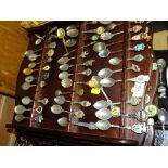 A LARGE QUANTITY OF SOUVENIR SPOONS ON WALL HANGING DISPLAY RACKS