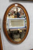 A MAHOGANY FRAMED BEVEL EDGED OVAL WALL MIRROR OVERALL SIZE - 78CM X 49CM