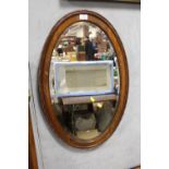 A MAHOGANY FRAMED BEVEL EDGED OVAL WALL MIRROR OVERALL SIZE - 78CM X 49CM