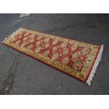 A 20TH CENTURY WOOLLEN RED CARPET RUNNER APPROX 232 X 76 CM