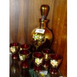 A VINTAGE RED AND GILT PAINTED GLASS DECANTER AND SHOT GLASS SET WITH FLORAL DETAIL