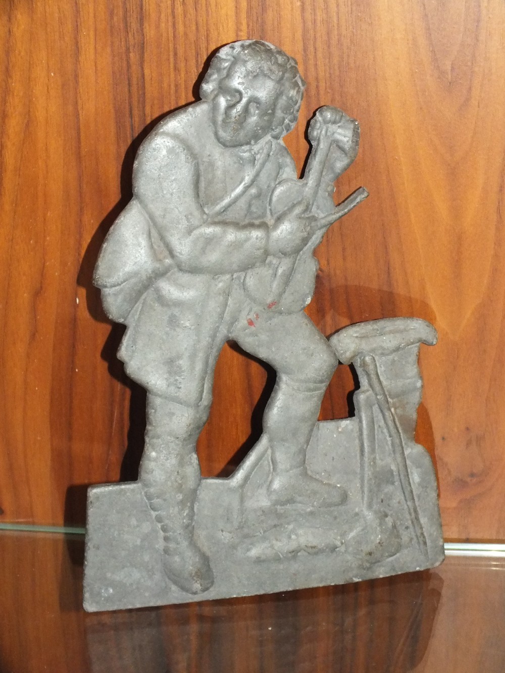 A VINTAGE CAST METAL PLAQUE IN THE FORM OF A MAN WITH A VIOLIN