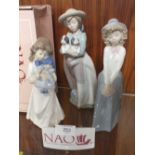 THREE NAO LADIES FIGURES HOLDING A DOLL, PUPPIES AND A PAIR OF MITTENS RESPECTIVELY, TOGETHER WITH A