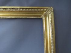A 19TH CENTURY DECORATIVE GOLD FRAME WITH CORNER EMBELLISHMENTS, having egg and dart design to outer