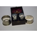 A CASED PAIR OF HALLMARKED SILVER NAPKIN RINGS AND TWO LOOSE NAPKIN RINGS