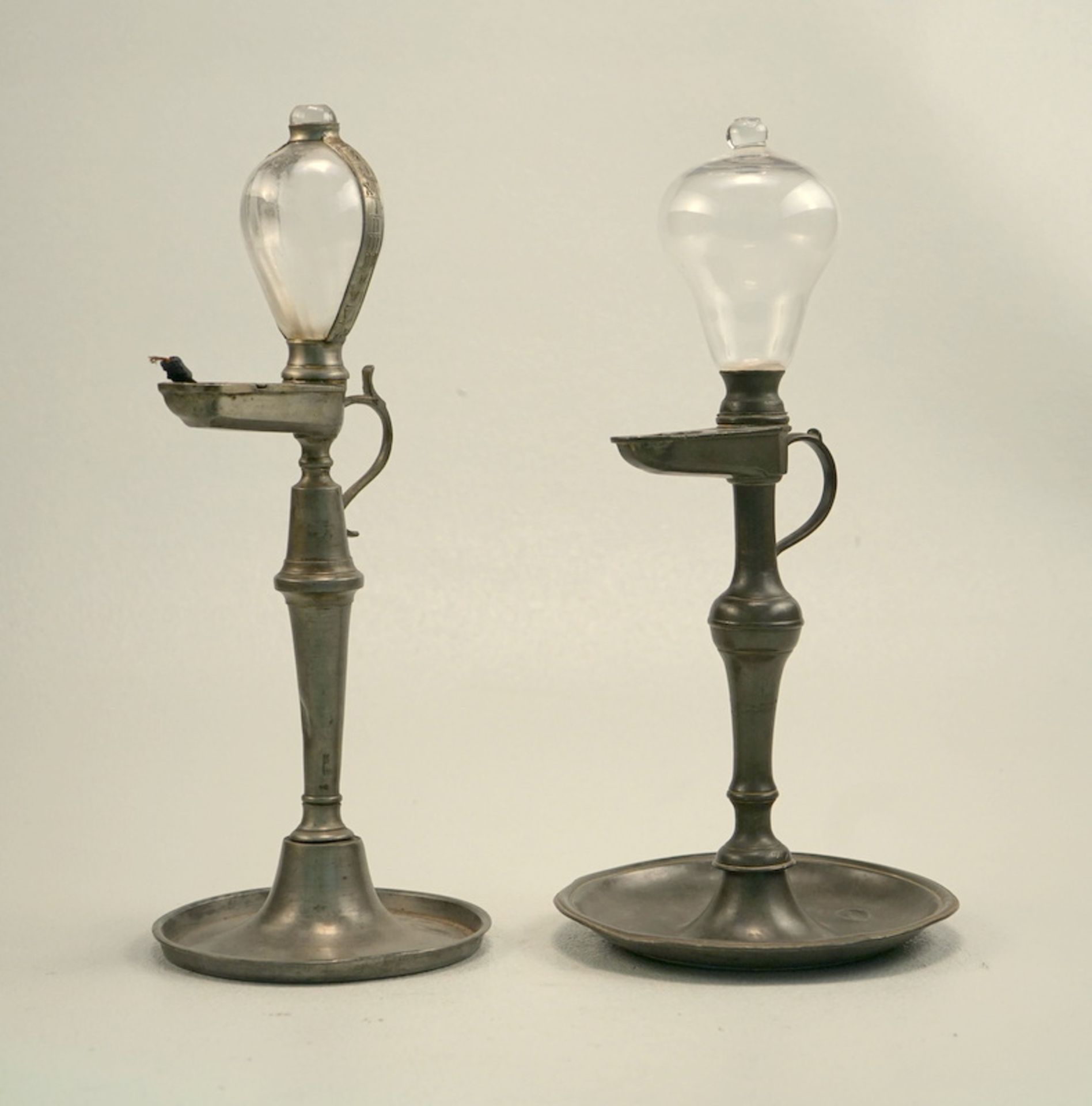 Zwei Öllampen des 19.Jhd.,Zinn und geblasenes Glas, Höhe jeweils ca. 35cm, eine Lampe am Griff