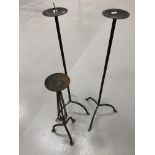 A pair of wrought iron candle holders height 92cm and a steel candle holder height 64cm.