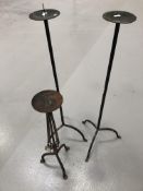 A pair of wrought iron candle holders height 92cm and a steel candle holder height 64cm.