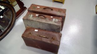 Three vintage leather suitcases.