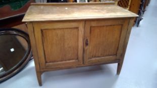 An oak two door cupboard on short tapering legs. Height 73.5cm width 93.5cm depth 46cm