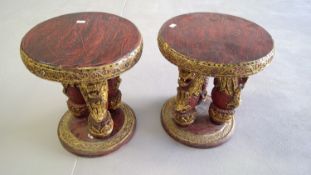 A pair of southeast Asian lacquer occasional tables with merlion supports, height 39cm diameter