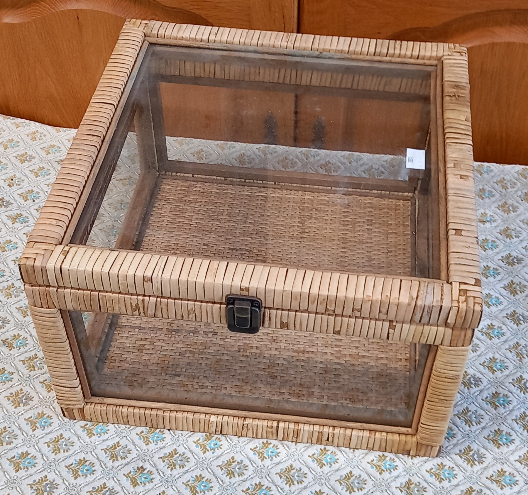 A Benjara glass case with rattan woven frame.