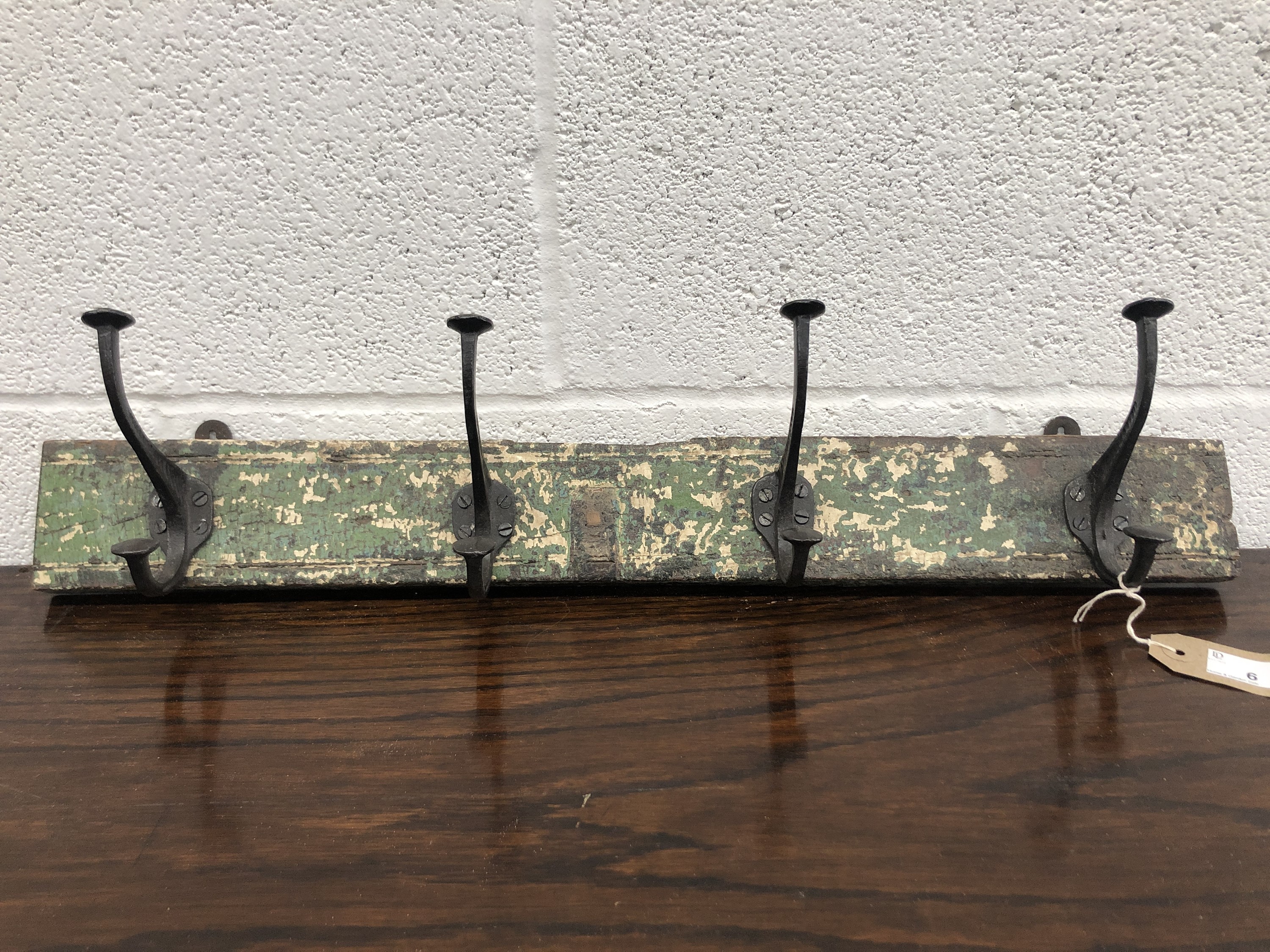 A set of metal coat hooks, attached to a rectangular wood panel. The hooks previously purchased from
