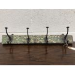 A set of metal coat hooks, attached to a rectangular wood panel. The hooks previously purchased from