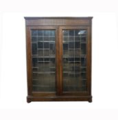 An oak bookcase, circa 1920's, with a pair of lead lined glazed doors, worm to back, height 140cm,