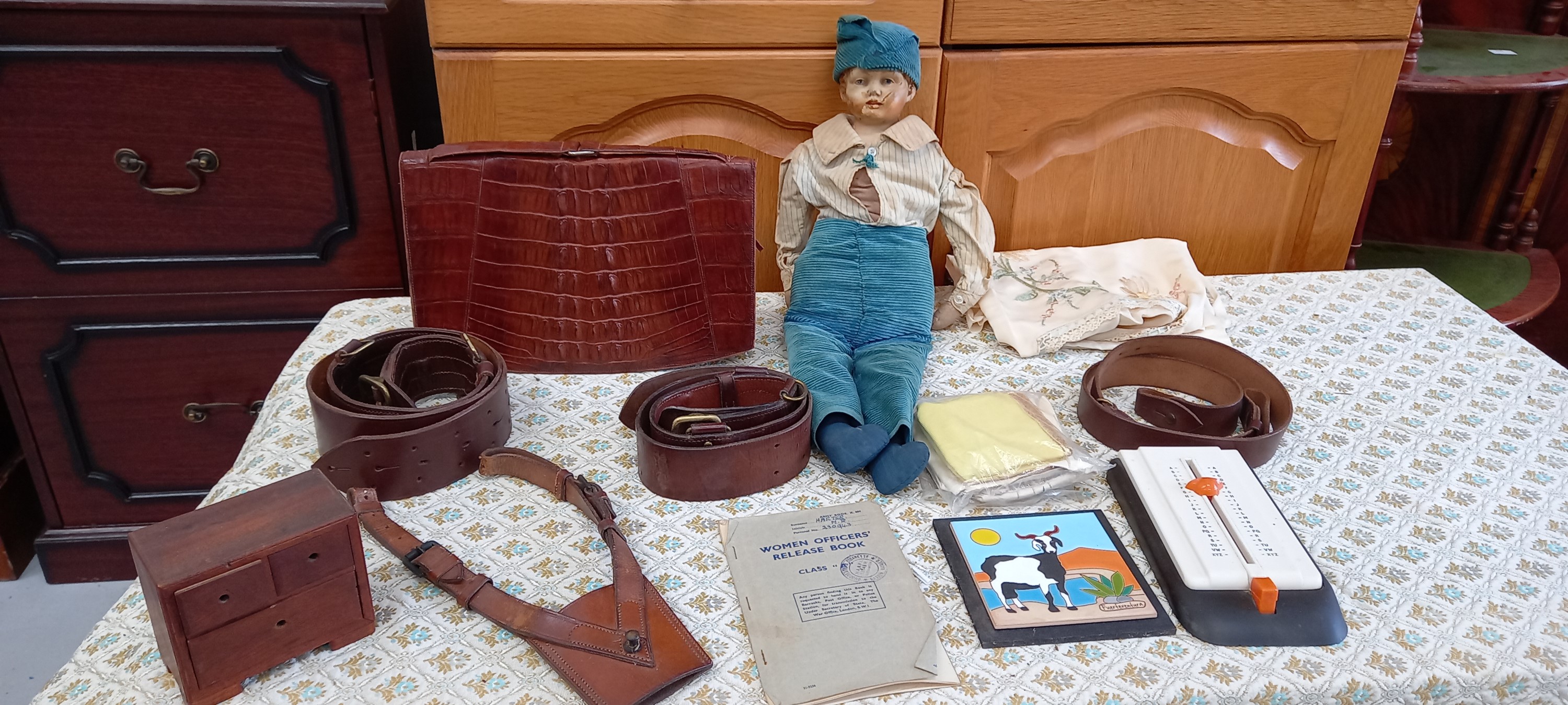 A crocodile skin handbag, a doll with a ceramic head, a gunsliner leather belt and other leather