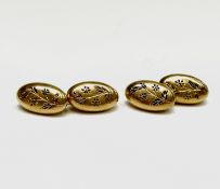 A pair of late 19th-century gold cuff-links, each head is decorated with grasses and flowers, the