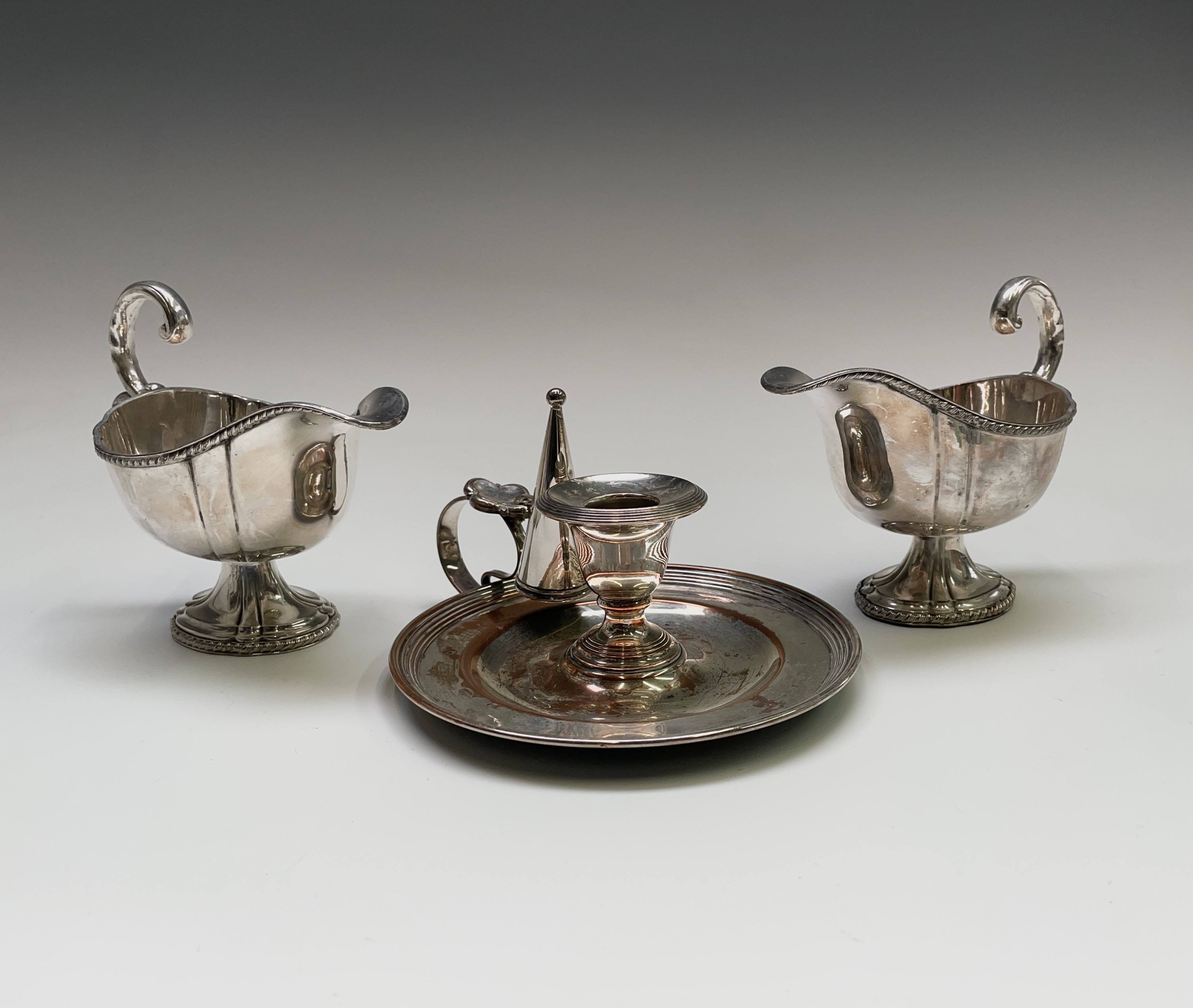 A pair of Sheffield plated sauce boats with gadrooned borders and a Sheffield plated chamberstick,