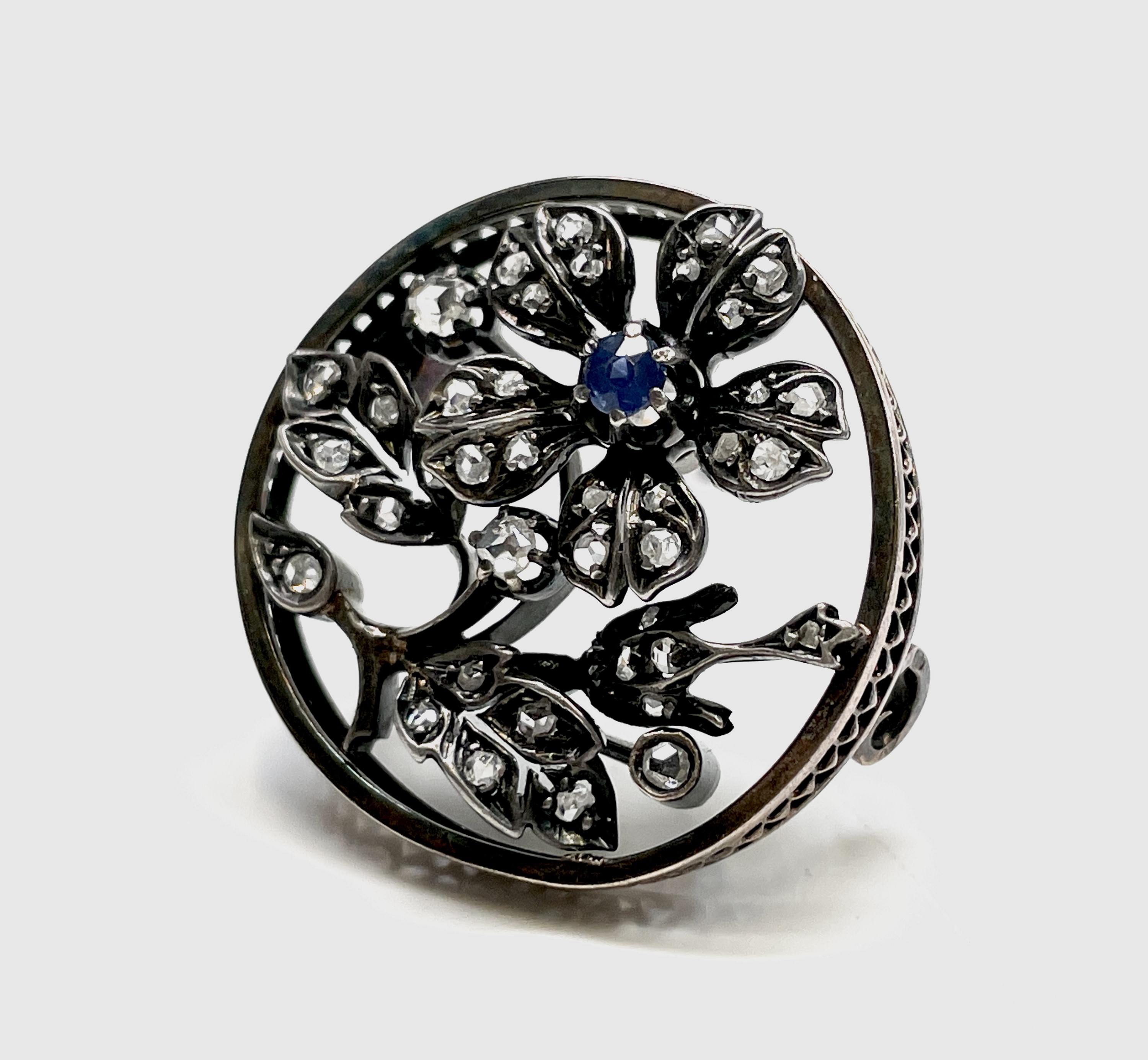 A late Victorian gold flower brooch, silver set with diamonds and a sapphire 27mm diameter 6.8gm