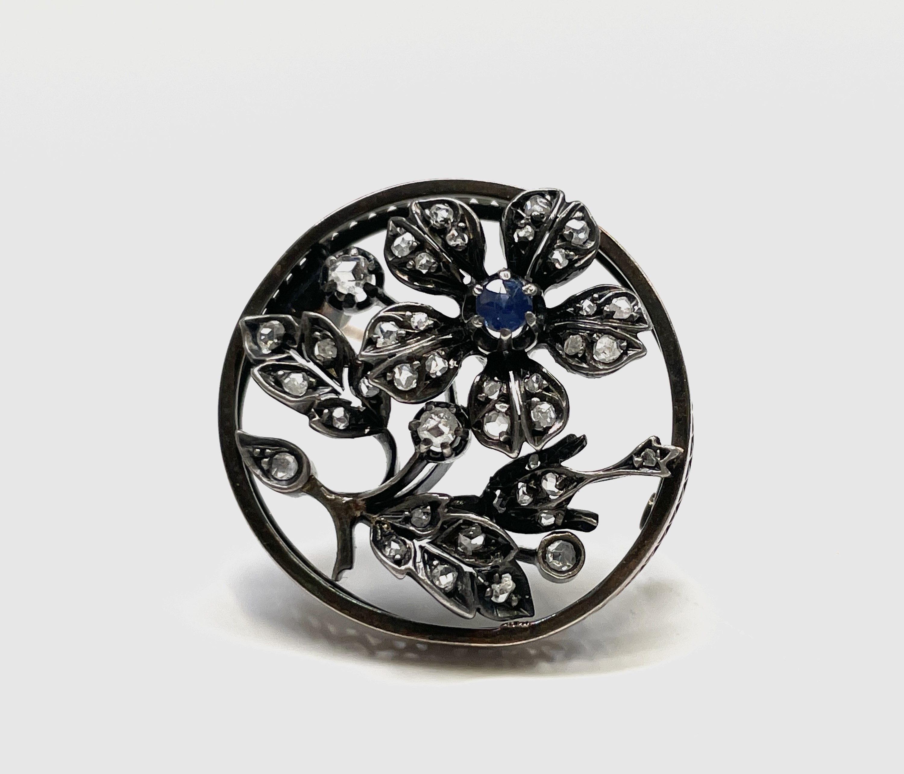 A late Victorian gold flower brooch, silver set with diamonds and a sapphire 27mm diameter 6.8gm - Image 2 of 2