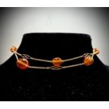 A delicate gold necklace with spaced pierced gold links and carnelian beads 14.9gm UK Postage: £17.0