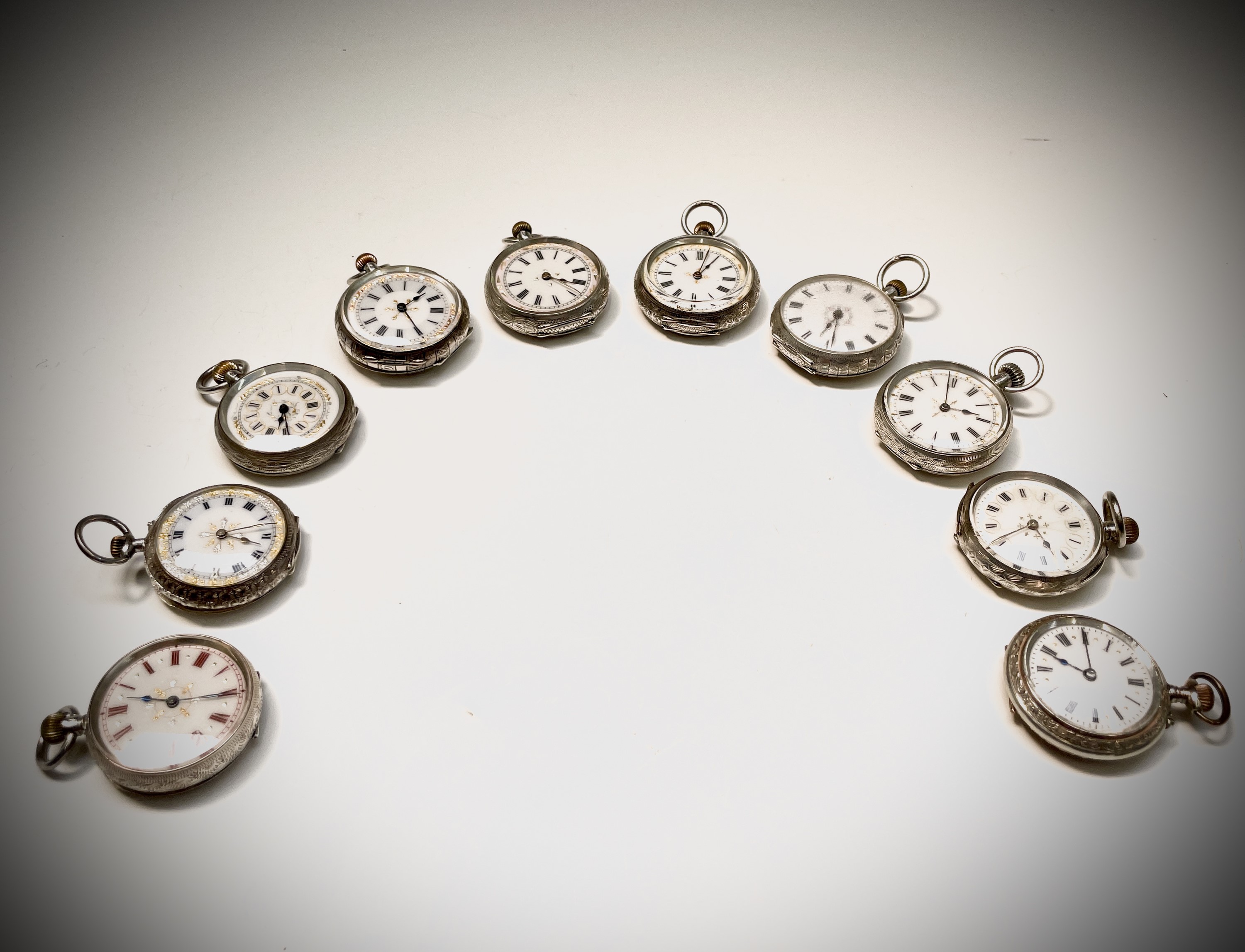 Ten silver cased keyless fob watches each with an ornamental dial and each with engraved decoration.