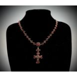 A Victorian garnet necklace with a line of stone set trefoils centred by a garnet cluster from which