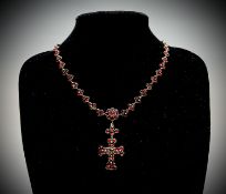 A Victorian garnet necklace with a line of stone set trefoils centred by a garnet cluster from which