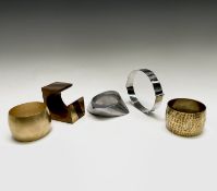 Four modernist bangles in cast aluminium, hammered brass, inlaid wood, and matt gold coloured metal,