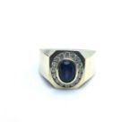 A 14ct yellow gold and cz gents ring, set with an oval synthetic sapphire and small white CZs in a