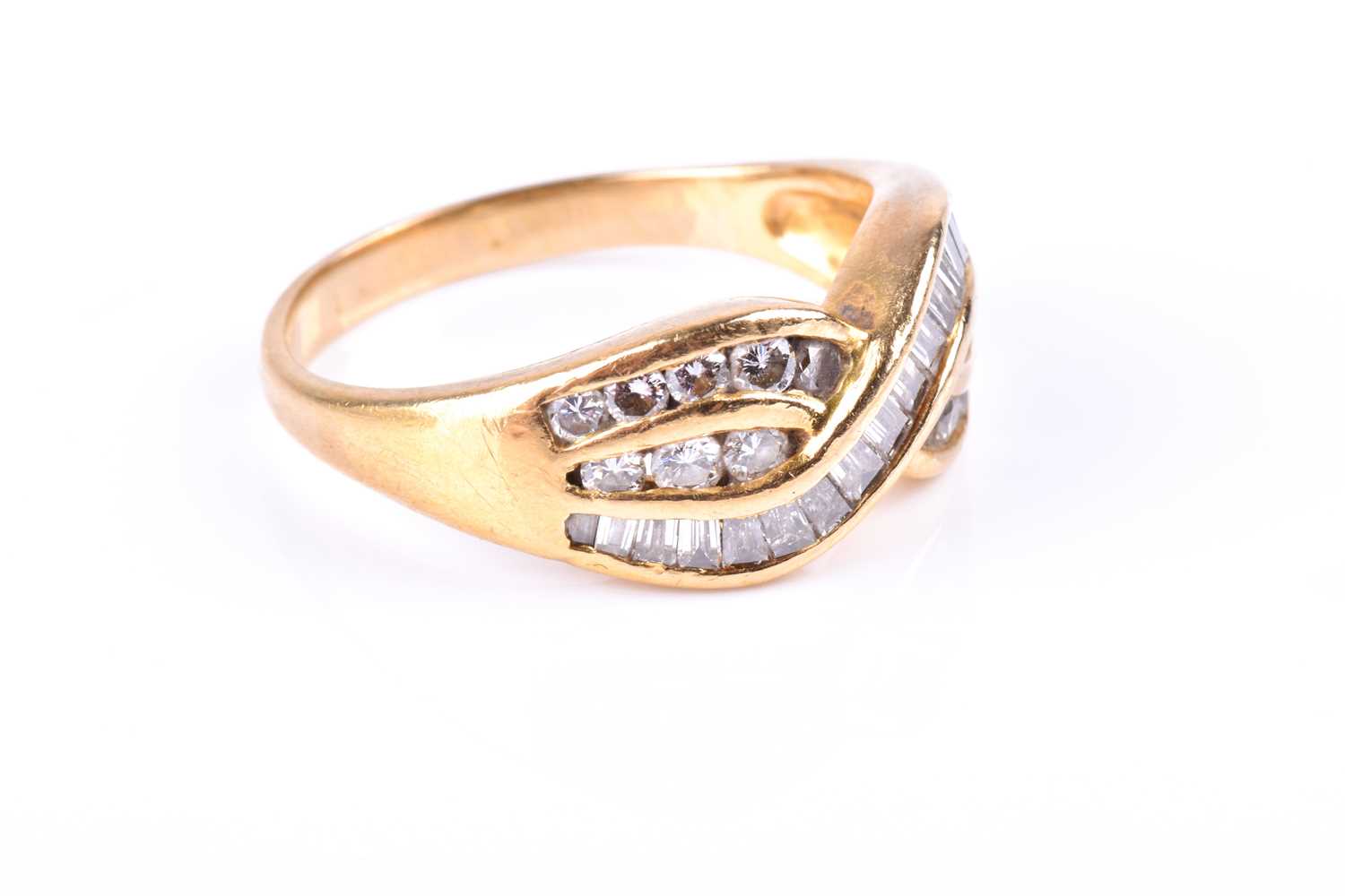 A yellow metal and diamond crossover ring, channel-set with mixed baguette-cut and round-cut - Image 2 of 4