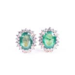 A pair of diamond and emerald cluster earrings, set with mixed oval-cut emeralds of approximately