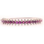 A fine diamond and ruby bangle bracelet, set with a row of mixed-cut rubies of approximately 3.70