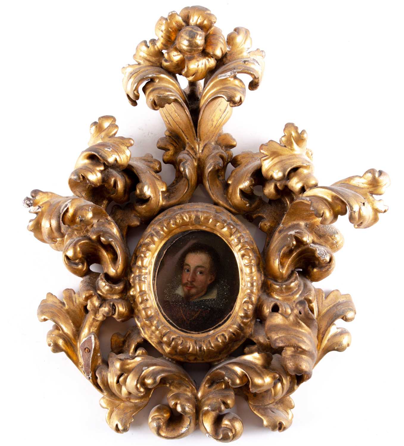 A 17th century oval miniature portrait of a nobleman, painted on wood, in an elaborate scrolling