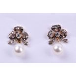 A pair of diamond and pearl drop earrings, the silver set gold-backed bow-shaped mounts inset with