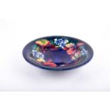 A Walter Moorcroft open dish in the Orchid pattern, with tube-lined floral decoration on a blue