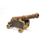 A 19th century cast iron model of a naval cannon, 84 cm long, mounted to a wooden carriage (a/f).