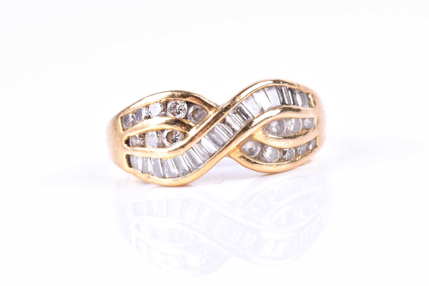 A yellow metal and diamond crossover ring, channel-set with mixed baguette-cut and round-cut
